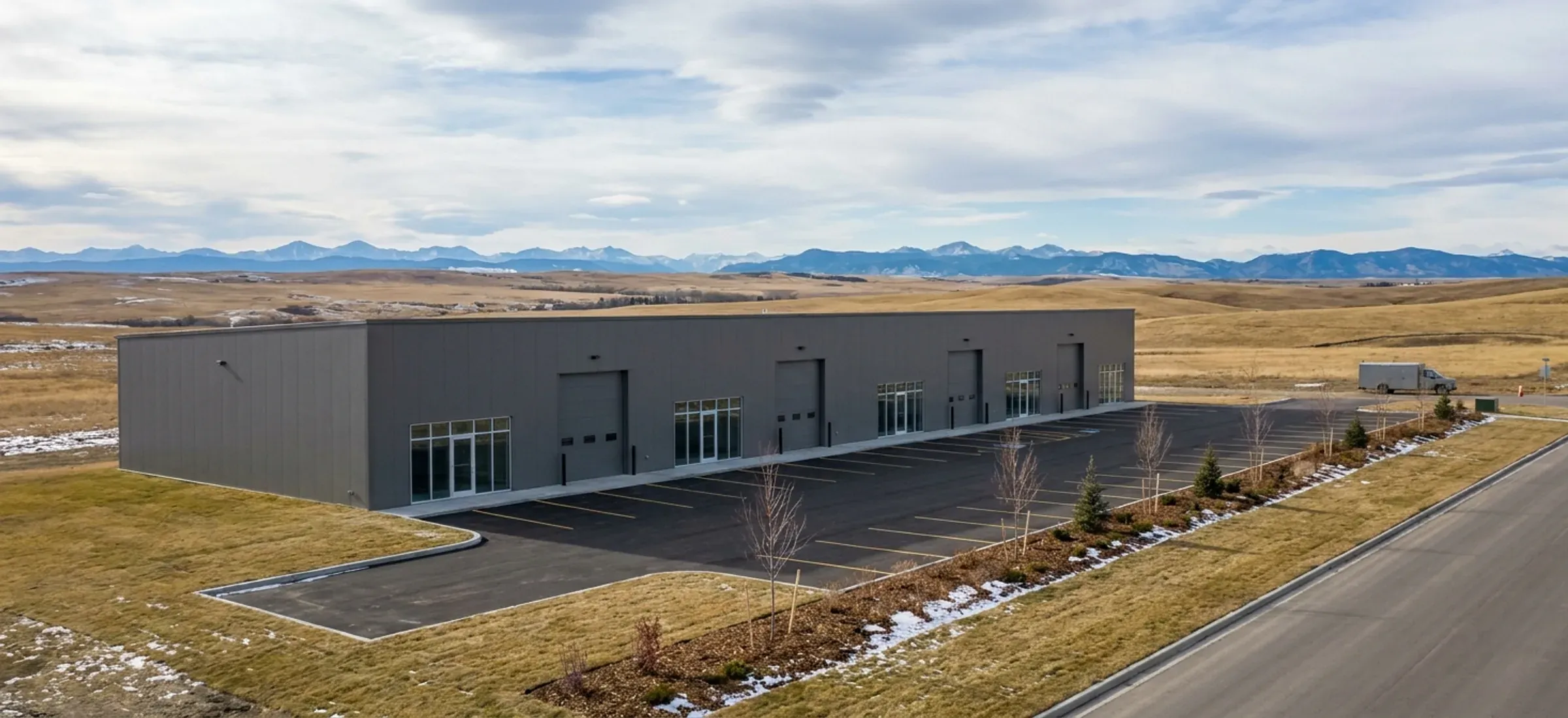 A steel flex commercial building with several bay doors and storefront units on open prairie