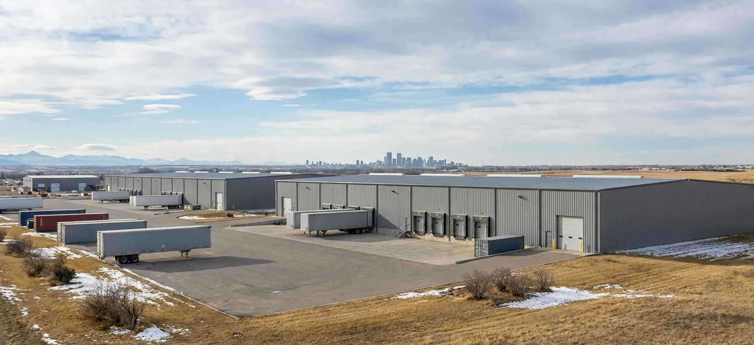 Steel industrial buildings in a business park with a city skyline faint in the distance