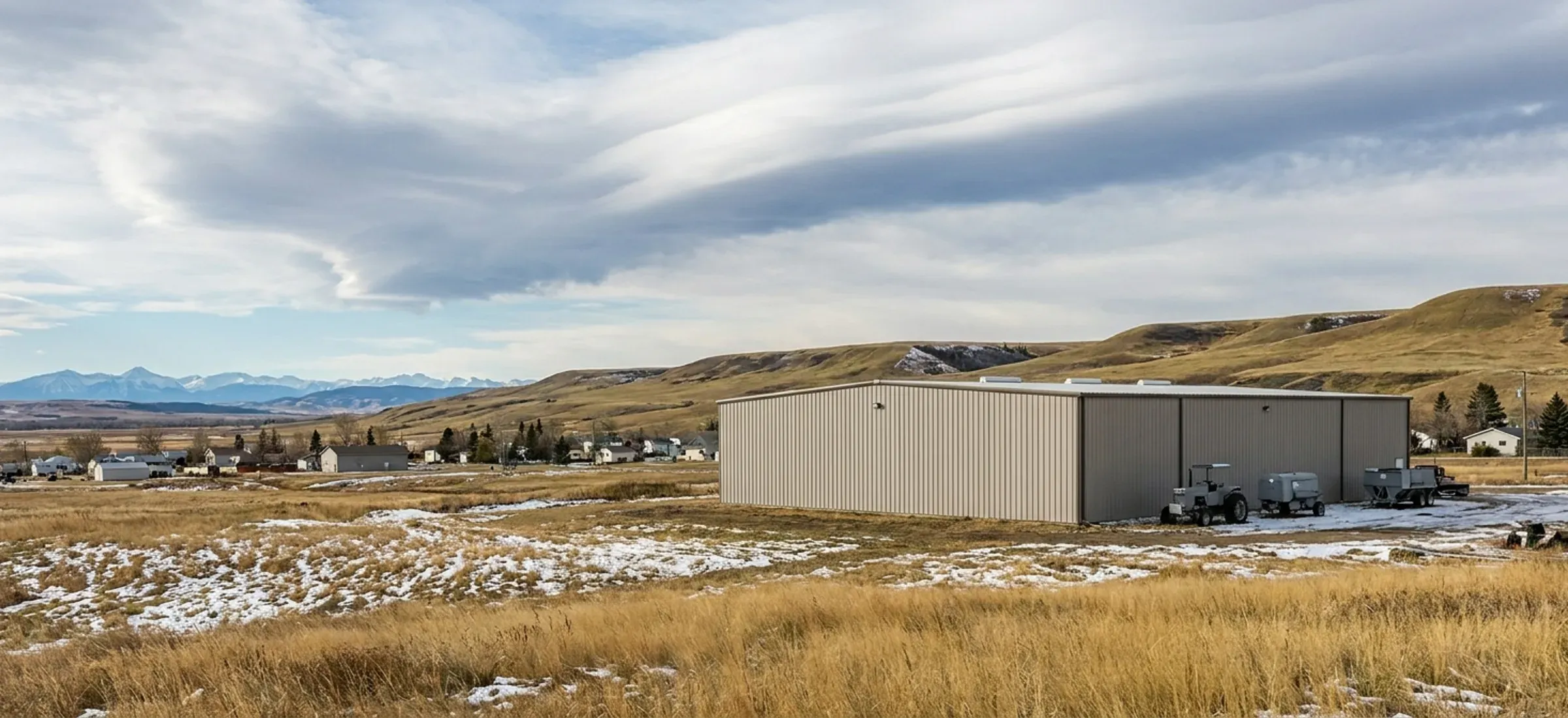 A steel building in a river valley town with foothills and mountains rising to the west